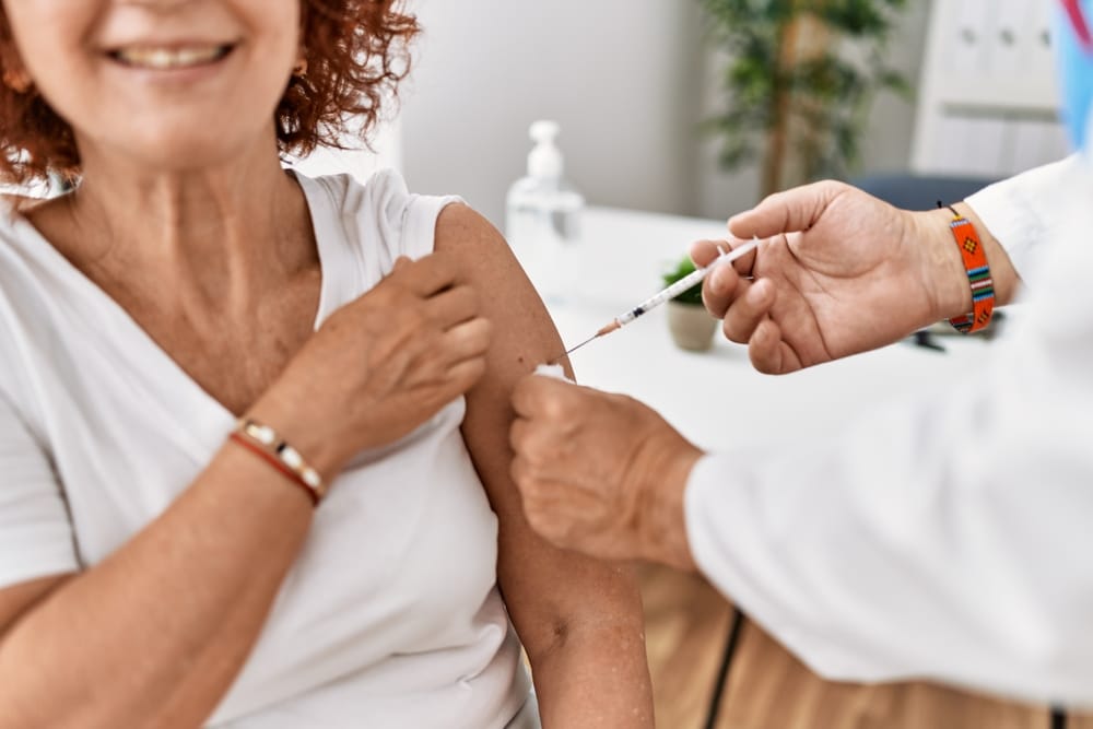 Middle,Age,Man,And,Woman,Wearing,Doctor,Uniform,Vaccinating,At - welltica.dk - Vejen til et bedre liv
