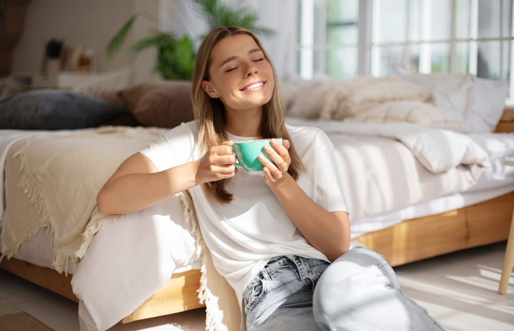 Young,Woman,Relaxes,In,Sunlight,,Holding,Teal,Mug,With,Eyes - welltica.dk - Vejen til et bedre liv