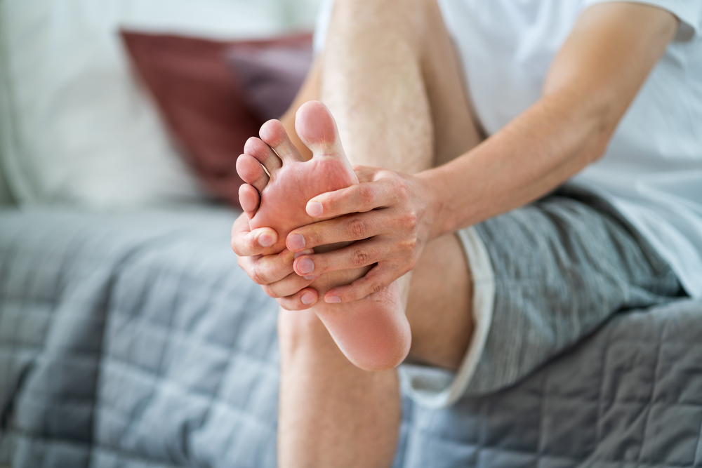 Foot,Pain,,Man,Suffering,From,Feet,Ache,In,Home,Interior, - welltica.dk - Vejen til et bedre liv
