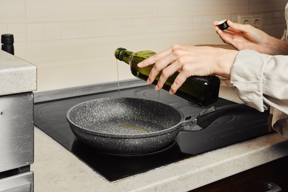 Unrecognizable,Woman,Pouring,Olive,Oil,On,Frying,Pan,From,The - welltica.dk - Vejen til et bedre liv