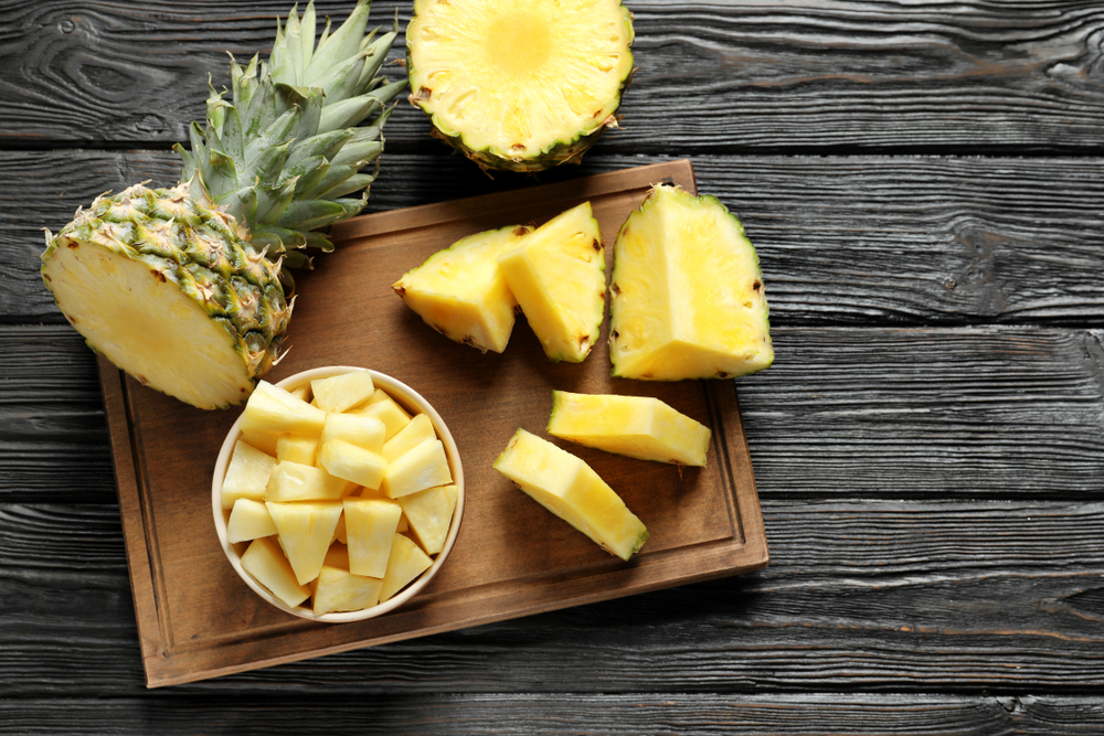 WoodenBoardWithFreshSlicedPineappleOnTableTopView - welltica.dk - Vejen til et bedre liv