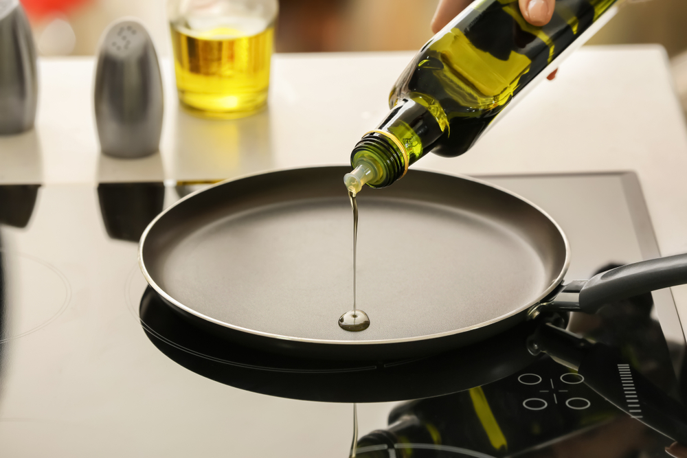 PouringOfOliveOilOntoFryingPanOnStove - welltica.dk - Vejen til et bedre liv