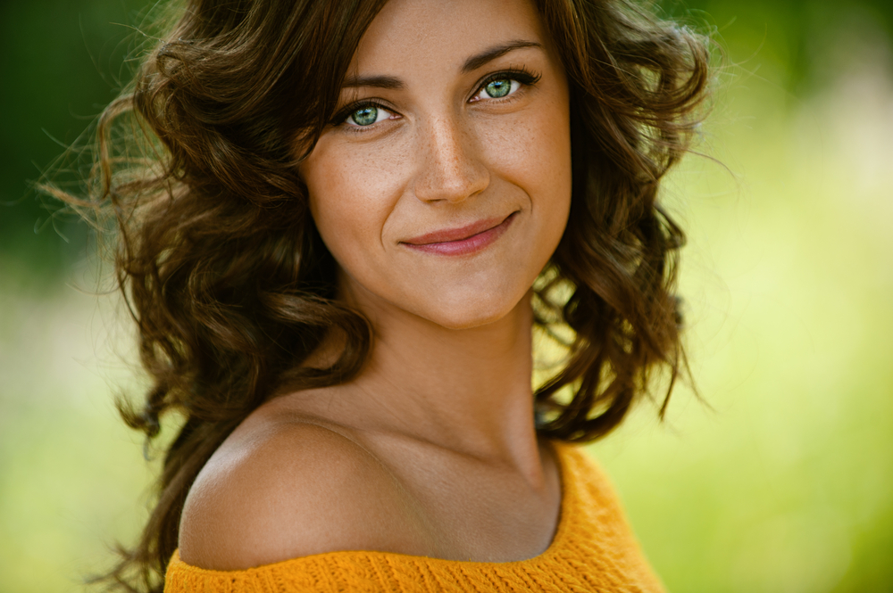 BeautifulYoungWomanClose-upInOrangeSweaterAgainstGreenOf - welltica.dk - Vejen til et bedre liv
