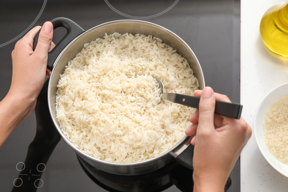 Woman,Cooking,Rice,On,Stove,In,Kitchen - welltica.dk - Vejen til et bedre liv