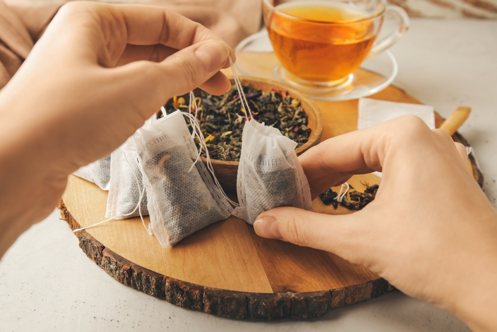 WomanWithTeaBagsAndDryLeavesOnLightBackground - welltica.dk - Vejen til et bedre liv
