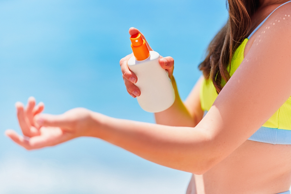 FemaleApplyingAndHoldingWhiteEmptyBottleBlankOfSunscreen - welltica.dk - Vejen til et bedre liv