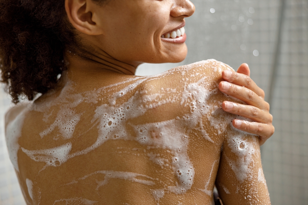 CloseUpOfSmilingAfricanWomanTakingAShowerWith - welltica.dk - Vejen til et bedre liv