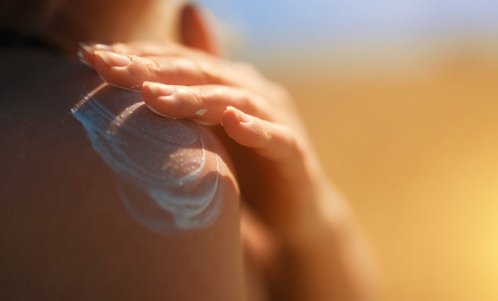WomanApplyingSunblockCreamOnHerShoulder - welltica.dk - Vejen til et bedre liv