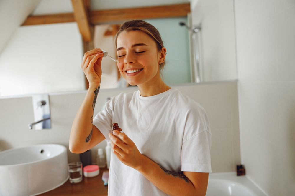 BeautifulYoungWomanApplyingCosmeticSerumOntoHerFaceIn - welltica.dk - Vejen til et bedre liv