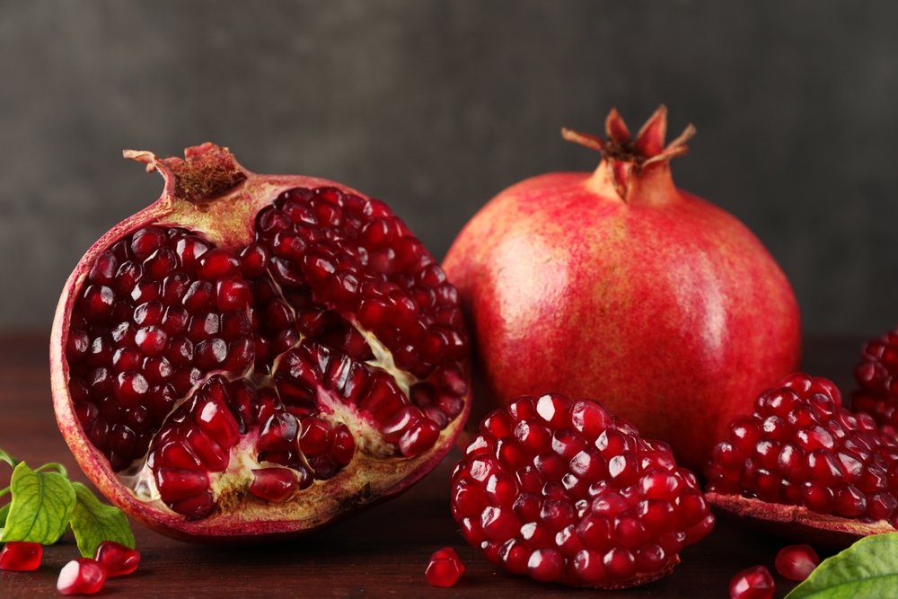 FreshPomegranatesAndGreenLeavesOnWoodenTableCloseup - welltica.dk - Vejen til et bedre liv