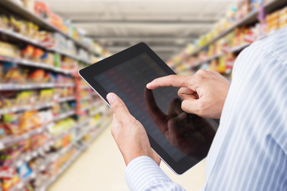 BusinessmanCheckingInventoryInMinimartOnTouchscreenTablet - welltica.dk - Vejen til et bedre liv