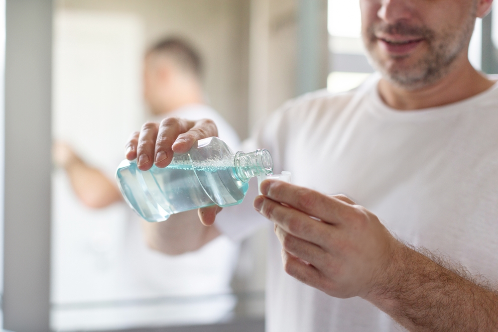 ManPouringBlueMouthwashForGoodDentalHealthAndFresh - welltica.dk - Vejen til et bedre liv