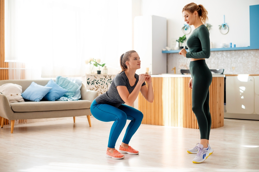 SportyFemaleTrainerWatchingYoungCaucasianWomanInActivewearSquatting - welltica.dk - Vejen til et bedre liv