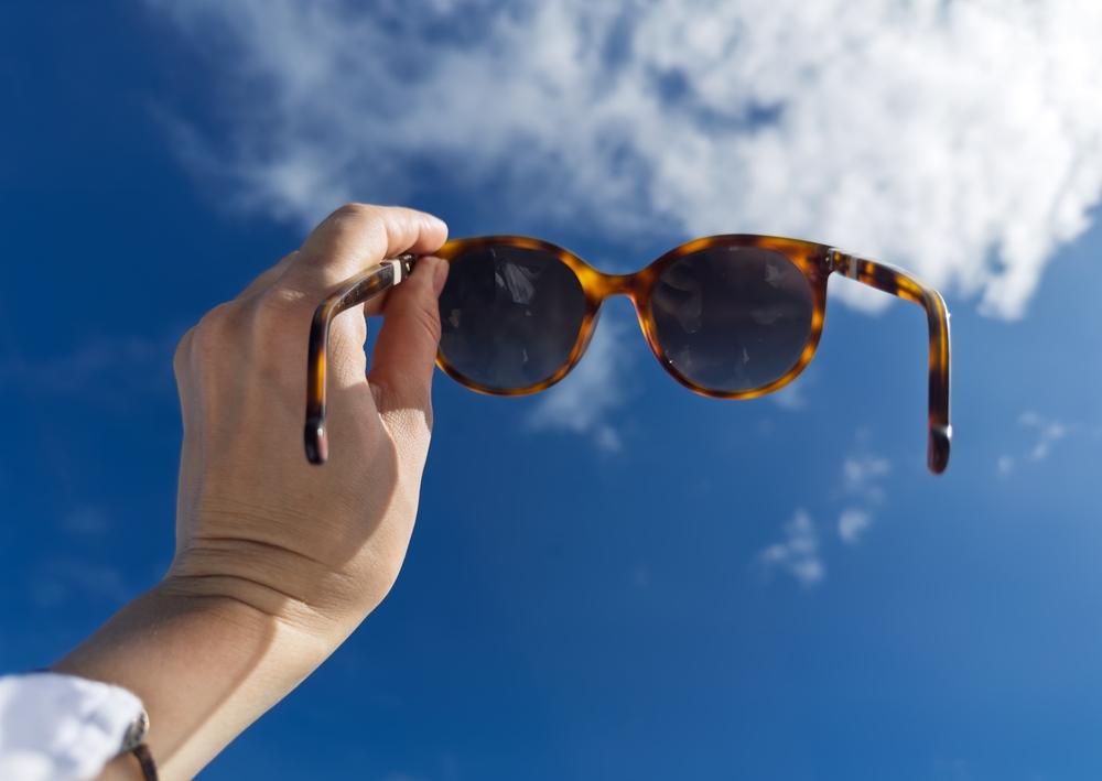 HandHoldingTrendySunglassesAgainstBlueSkyWithWhiteClouds - welltica.dk - Vejen til et bedre liv