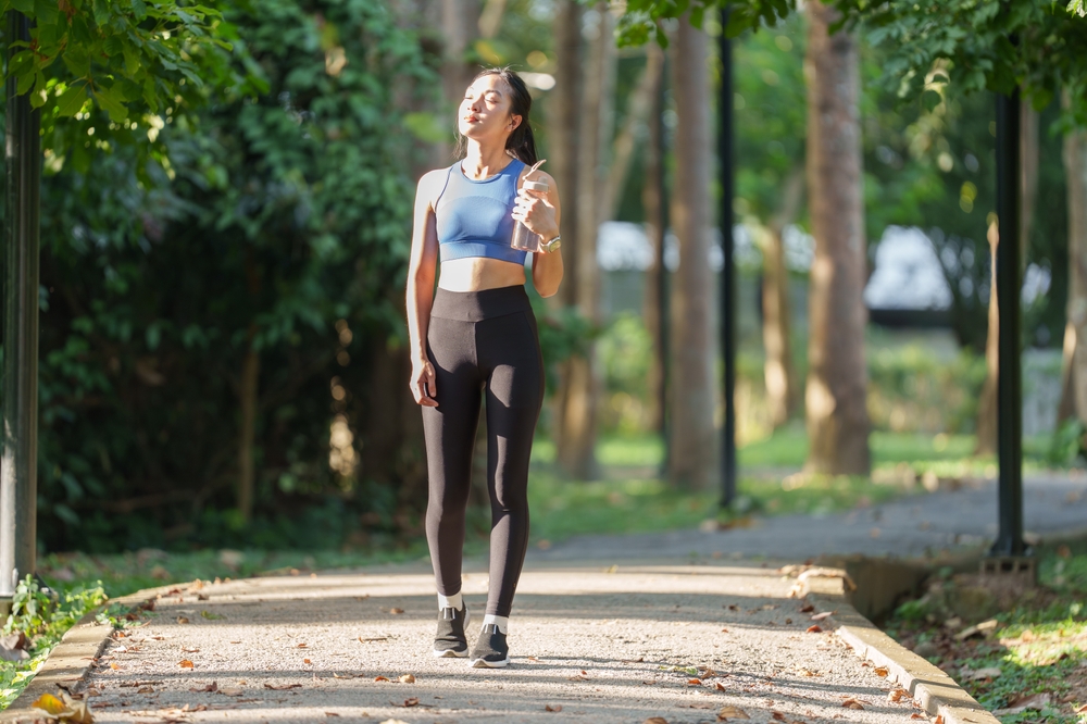 YoungAsianWomanDressedInSportswearWalksAlongAPark - welltica.dk - Vejen til et bedre liv