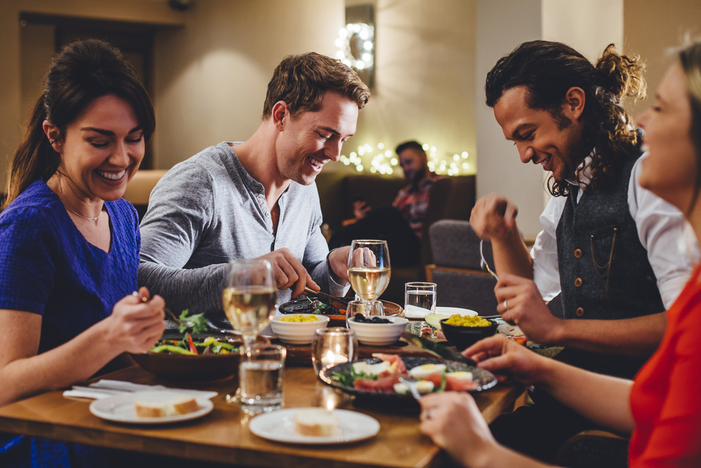 GroupOfFriendsEnjoyingAnEveningMealWithWineAt - welltica.dk - Vejen til et bedre liv