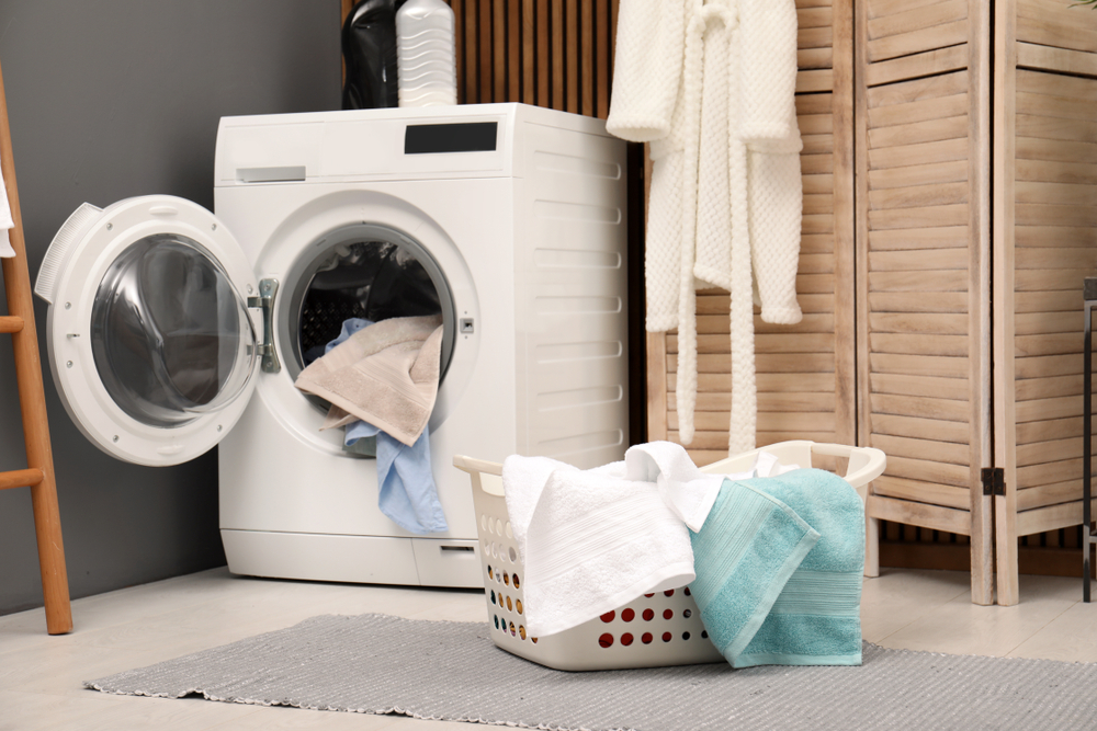 BasketWithDirtyTowelsOnWashingMachineInModernLaundry - welltica.dk - Vejen til et bedre liv