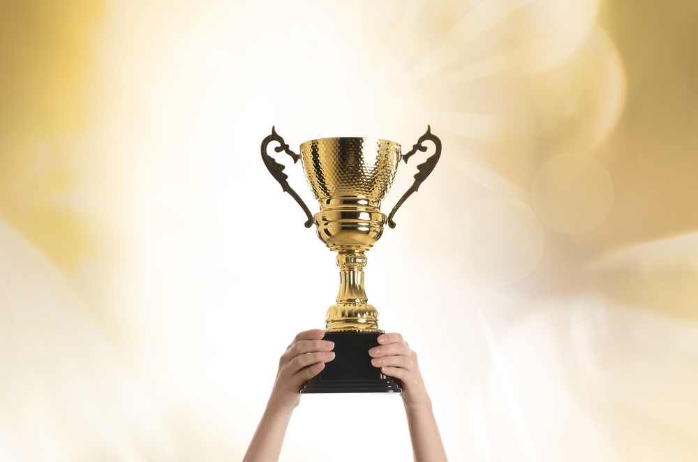 WomanHoldingGoldTrophyCupOnColorBackgroundCloseup - welltica.dk - Vejen til et bedre liv