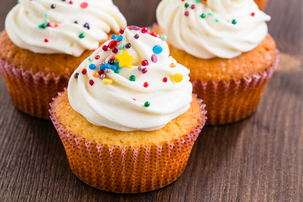 GourmetCupcakesWithWhiteButtercreamFrostingAndSprinklesOnWooden - welltica.dk - Vejen til et bedre liv