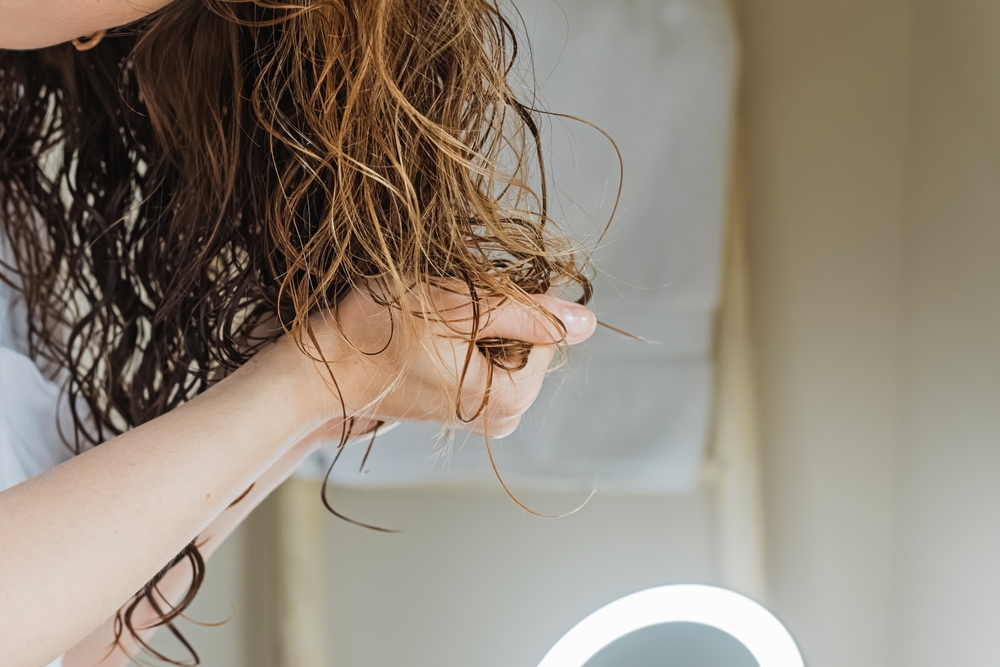 WomanScrunchingHerHairToFormCurlsApplyingCurlyMethod - welltica.dk - Vejen til et bedre liv