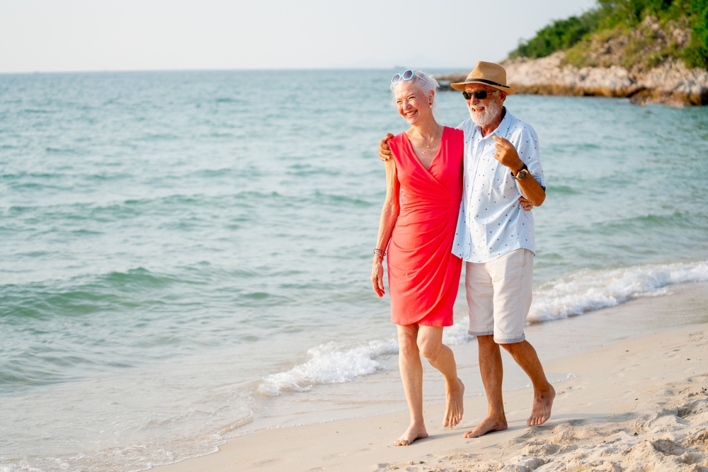 CaucasianSeniorManAndWomanWalkAlongTheBeachTogether - welltica.dk - Vejen til et bedre liv