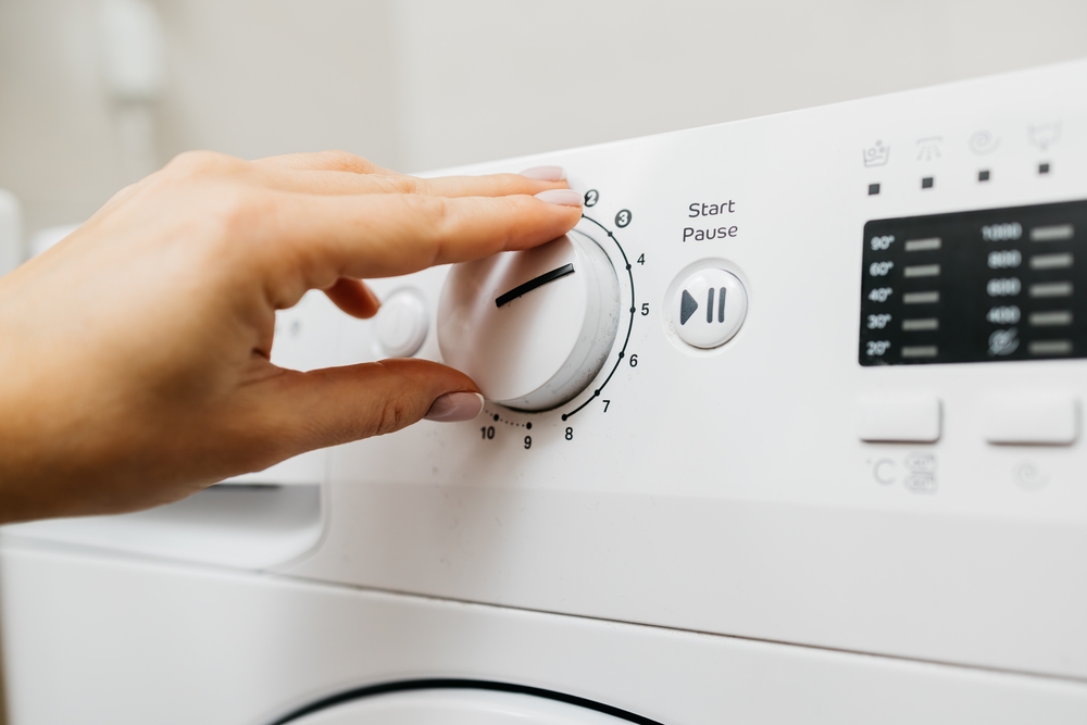 AWomanLoadsDirtyLaundryIntoTheWashingMachineAnd - welltica.dk - Vejen til et bedre liv