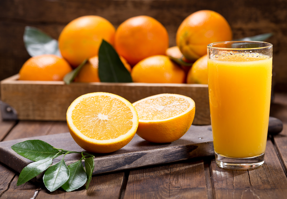 GlassOfFreshOrangeJuiceWithFreshFruitsOnWooden - welltica.dk - Vejen til et bedre liv