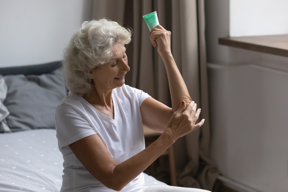 HappyMature60sWomanSitOnBedAtHomeApply - welltica.dk - Vejen til et bedre liv