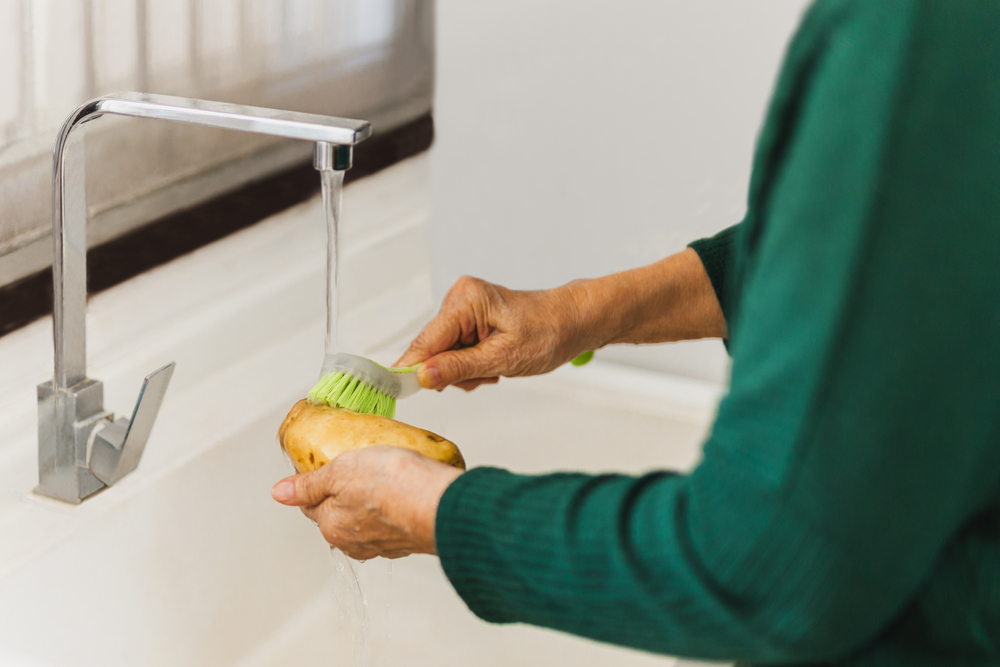 SeniorWomanHandWashingDirtOffHomegrownPotatoesWithA - welltica.dk - Vejen til et bedre liv