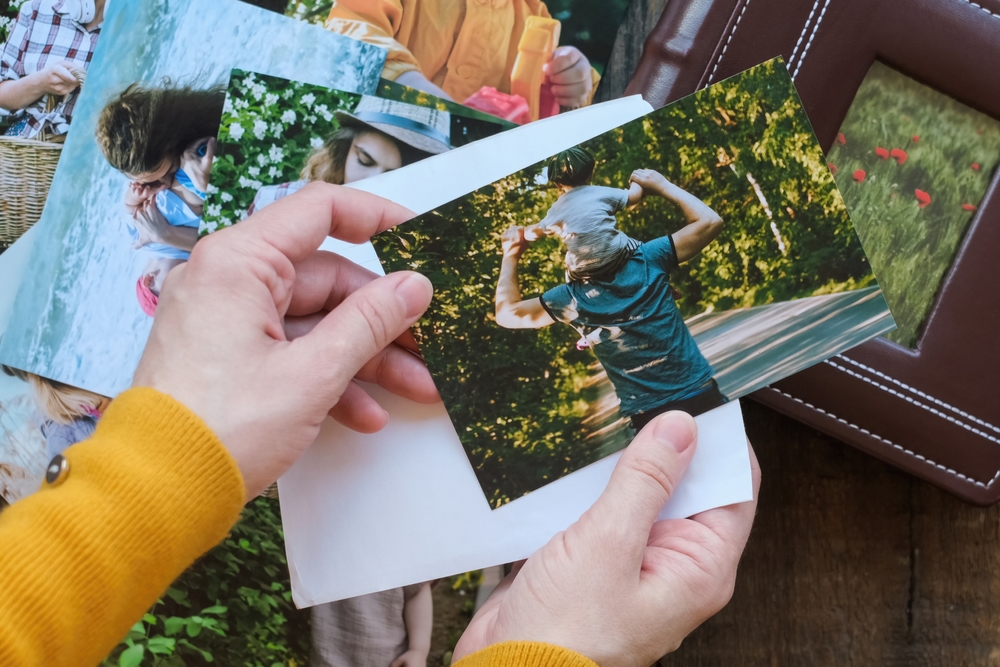 PersonLooksAtPrintedPhotosForFamilyPhotoAlbumOverhead - welltica.dk - Vejen til et bedre liv