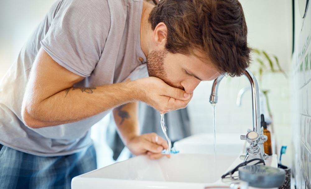 ManInBathroomBrushingTeethAndRinseWithWaterMorning - welltica.dk - Vejen til et bedre liv