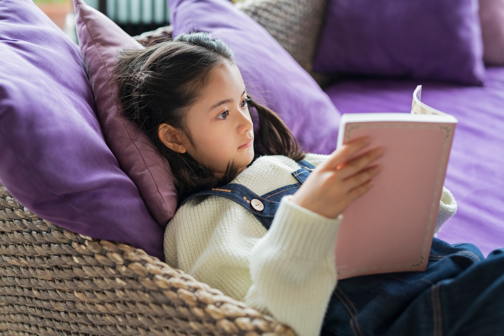 GirlReadingABookInTheLivingRoom - welltica.dk - Vejen til et bedre liv