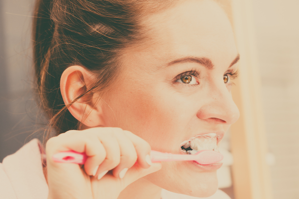 WomanBrushingCleaningTeethGirlWithToothbrushInBathroomOral - welltica.dk - Vejen til et bedre liv
