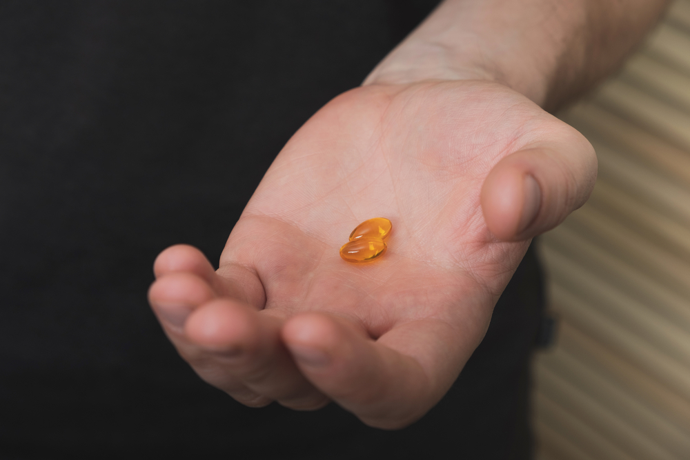 ManHoldingInHandYellowCapsulesVitaminDOmega3 - welltica.dk - Vejen til et bedre liv