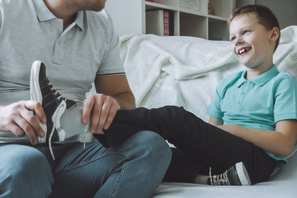 DadAndSonSittingOnCouchFatherHelpsChildTo - welltica.dk - Vejen til et bedre liv