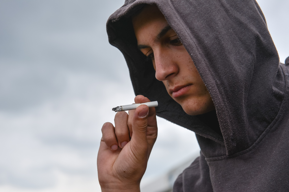 YoungManLookedAtTheCigaretteAndIsUndecidedWhether - welltica.dk - Vejen til et bedre liv