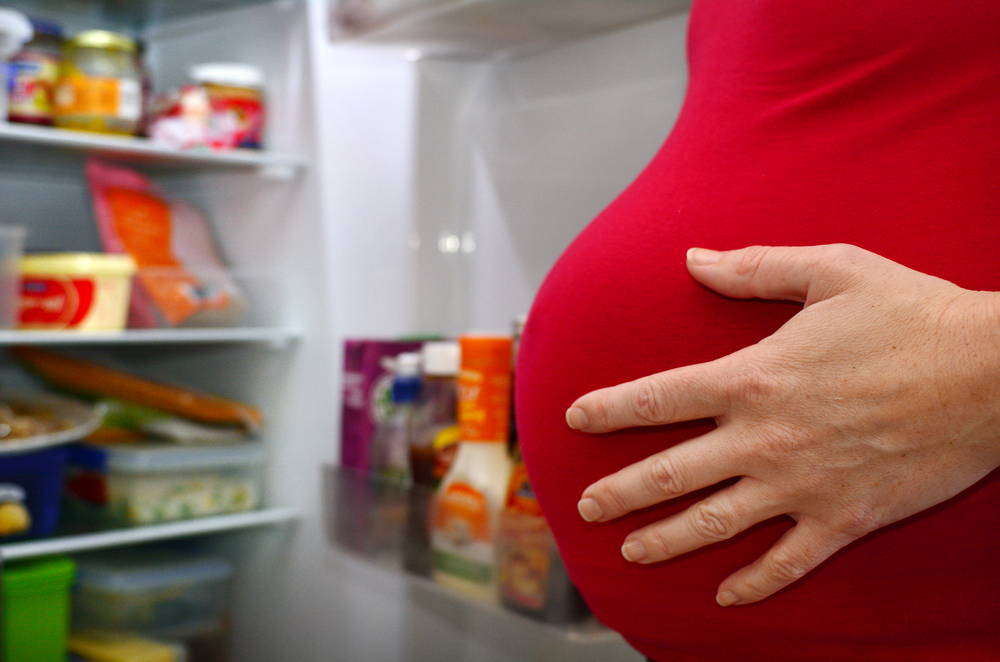 AHungryPregnantWomanStandingNearRefrigeratorLookingForFood - welltica.dk - Vejen til et bedre liv