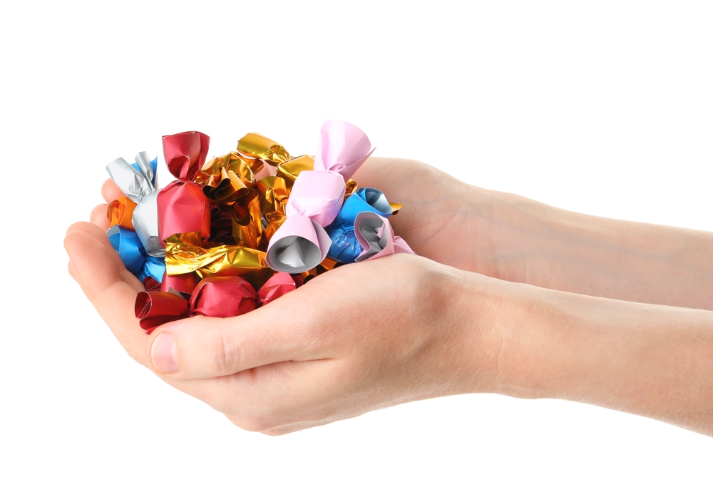 WomanHoldingHeapOfCandiesInColorfulWrappersIsolatedOn - welltica.dk - Vejen til et bedre liv
