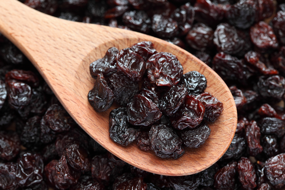 RaisinsInAWoodenSpoonOnRaisinsBackgroundClose-up - welltica.dk - Vejen til et bedre liv