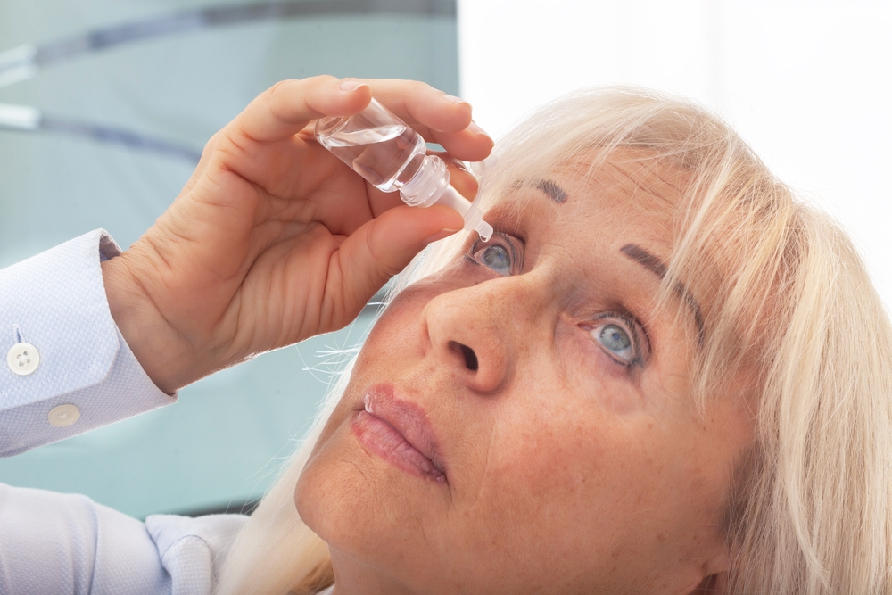 SeniorWomanDripsEyeDropsIntoHerEyesWomanSuffering - welltica.dk - Vejen til et bedre liv