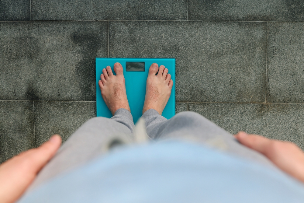 ManStandingOnWeightScaleMaleFeetOnGlassScales - welltica.dk - Vejen til et bedre liv