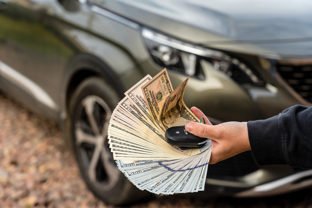 APersonWithMoneyAndCarKeyStandingFrontCar - welltica.dk - Vejen til et bedre liv