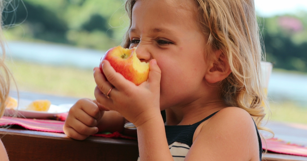ChildGirlEatingAppleOutsideChewing - welltica.dk - Vejen til et bedre liv