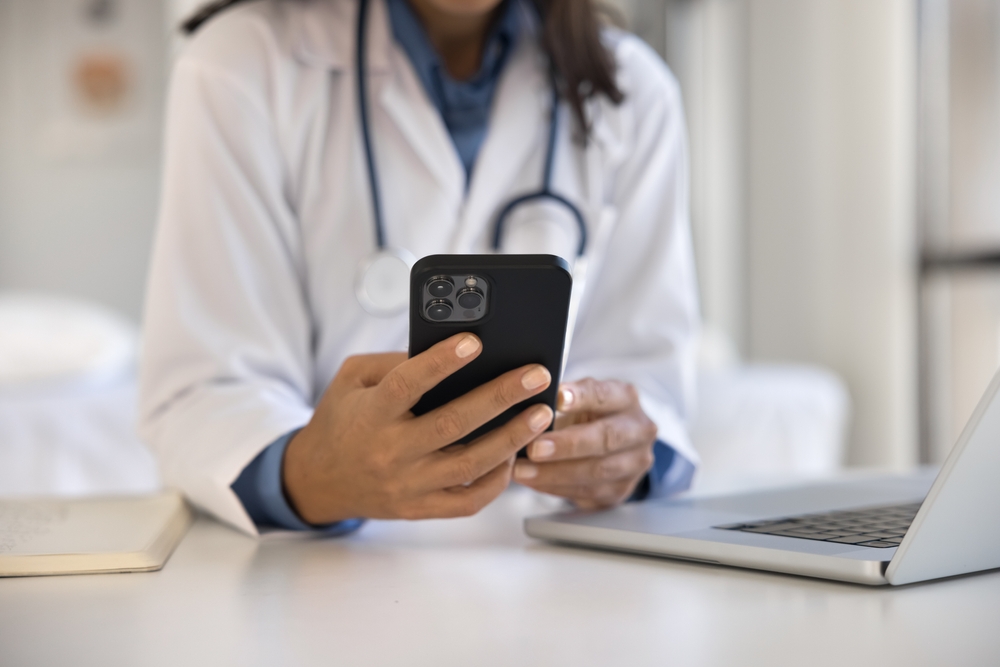 CloseUpFemaleDoctorUsingSmartphoneAtWorkplaceAccessRecords - welltica.dk - Vejen til et bedre liv