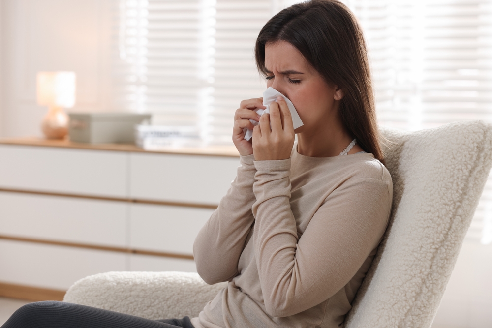 YoungWomanWithTissueBlowingRunnyNoseAtHomeSpace - welltica.dk - Vejen til et bedre liv