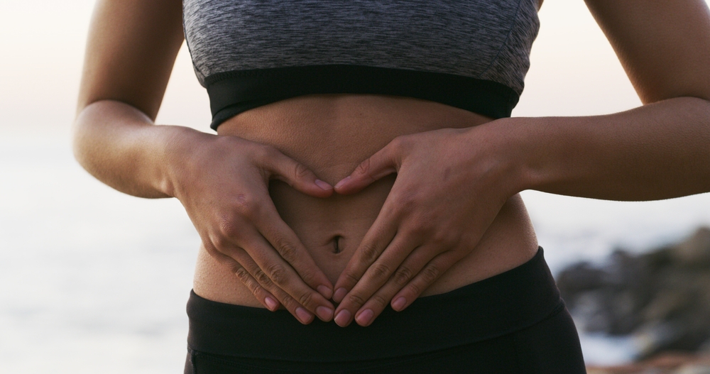 WomanHandsAndFitnessWithStomachForGutHealthBalance - welltica.dk - Vejen til et bedre liv