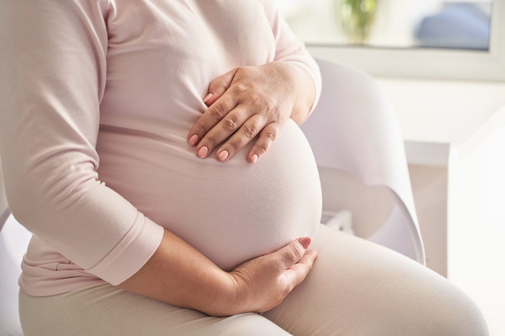PregnantCaucasianYoungFemaleSittingOnSofaInComfortableHome - welltica.dk - Vejen til et bedre liv