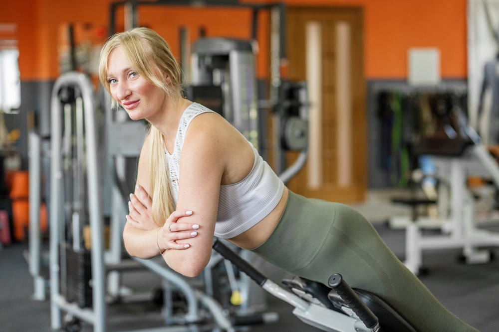 ConfidentYoungWomanPerformingBackExtensionOnHyperextensionBenchInside - welltica.dk - Vejen til et bedre liv