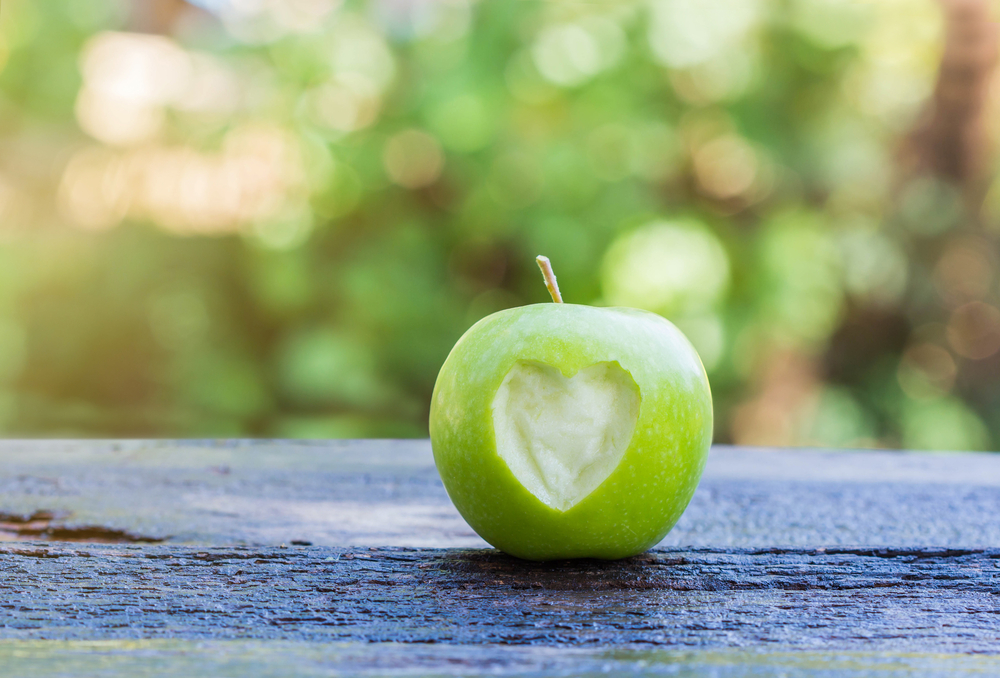FreshGreenAppleWithHeartShapeOnWoodenTable - welltica.dk - Vejen til et bedre liv