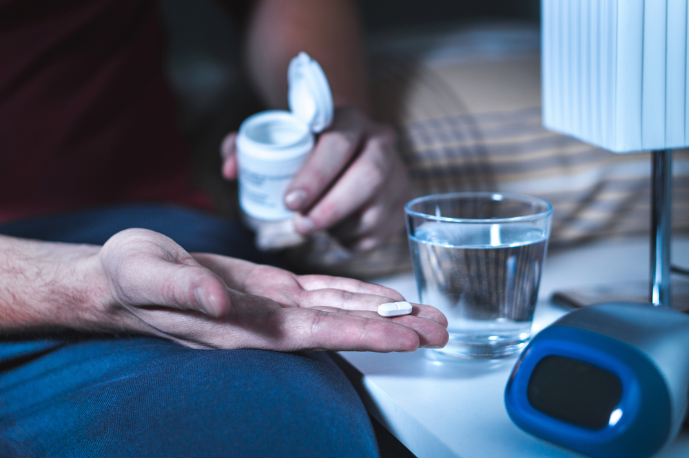 ManSittingOnBedAboutToTakeSleepingPillOr - welltica.dk - Vejen til et bedre liv